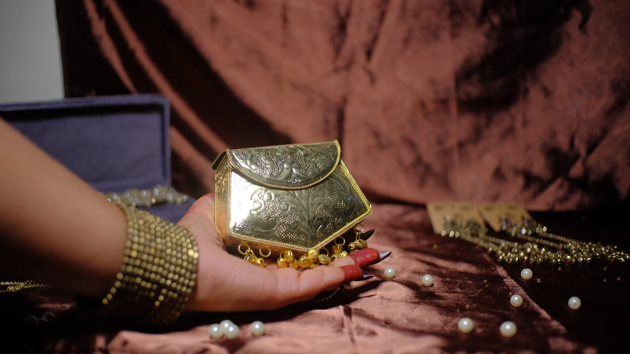 Gold embellished evening bag held against chocolate satin